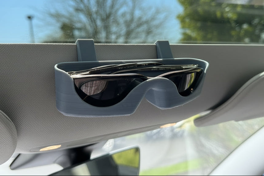 Sunglasses in a car's visor holder with a blurred outdoor background